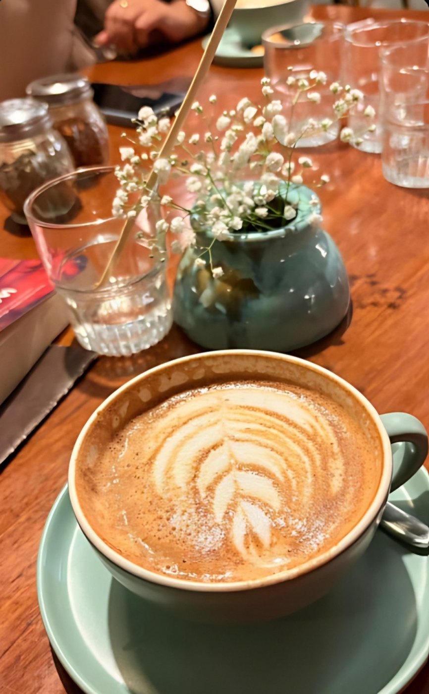 Latte served with a small flower vase